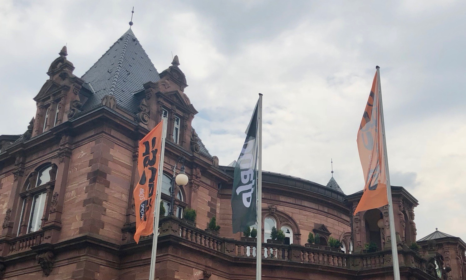 Flags with the django logo in front of a sandstone building